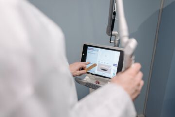 A medical professional using a laser machine with a touch screen interface in a clinical setting.